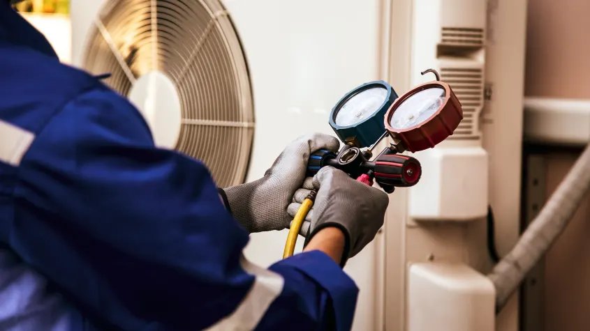 Technician connecting refrigerant gauges during a service call